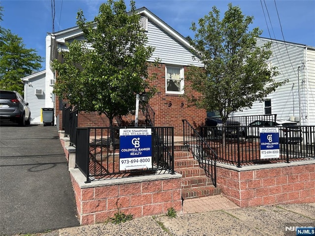 view of front of home featuring brick siding and fence