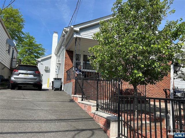 view of front of property featuring brick siding, a chimney, and cooling unit