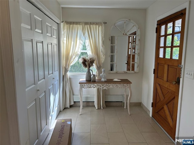 foyer entrance featuring light tile patterned floors, baseboards, and plenty of natural light