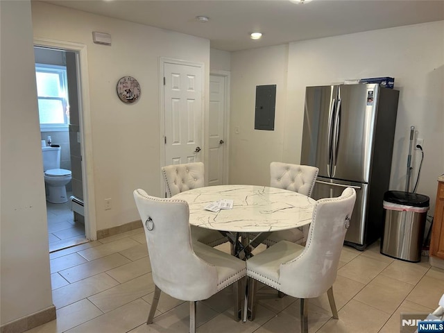 dining space with baseboards, a baseboard radiator, light tile patterned floors, and electric panel