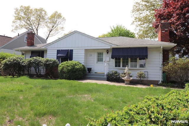 ranch-style house with a chimney, board and batten siding, and a front yard