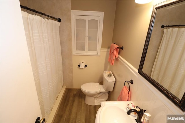 bathroom with a sink, wood finished floors, toilet, and a shower with curtain