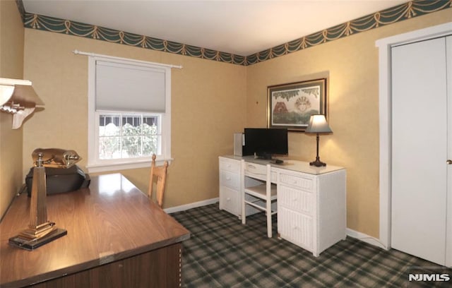 office space with baseboards and dark colored carpet