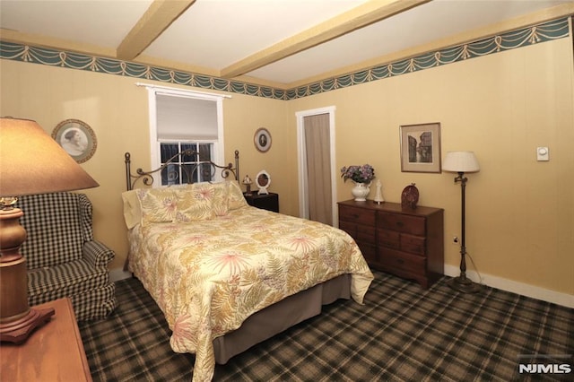 bedroom featuring baseboards, dark colored carpet, and beam ceiling