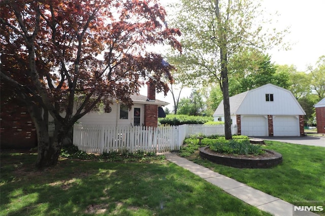 view of side of property with a chimney, a lawn, an outbuilding, a detached garage, and fence
