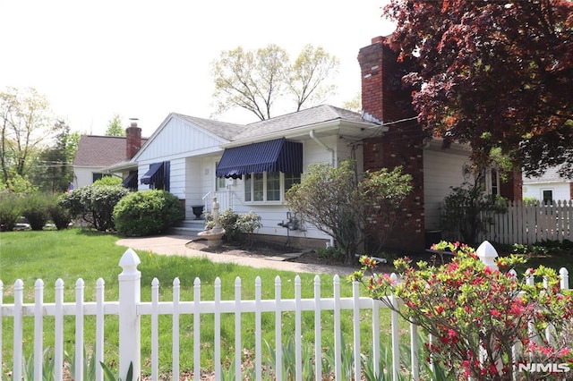 view of front of property featuring a fenced front yard, a chimney, and a front yard
