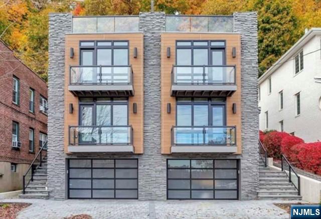 exterior space with stairway, stone siding, and a garage