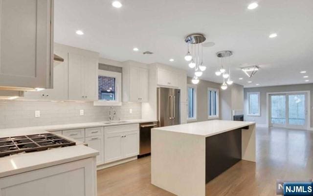kitchen featuring pendant lighting, open floor plan, a center island, tasteful backsplash, and stainless steel appliances