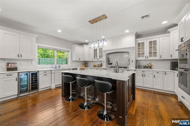 kitchen with wine cooler, stainless steel double oven, white cabinets, and recessed lighting
