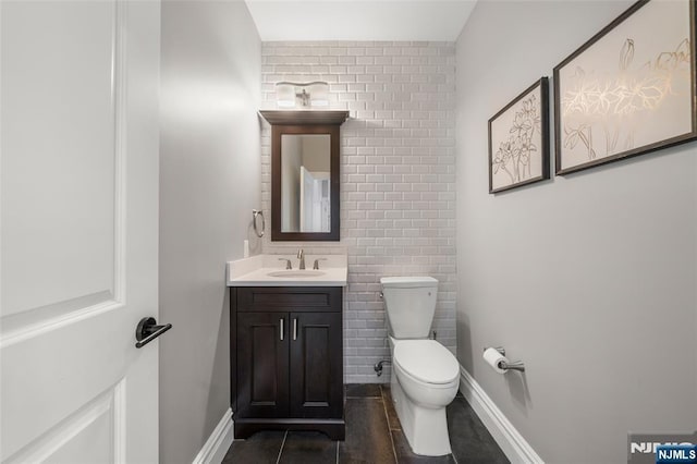 half bath featuring toilet, vanity, tile patterned flooring, and baseboards