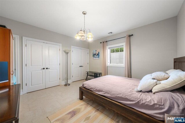 bedroom featuring multiple closets, a chandelier, and baseboards