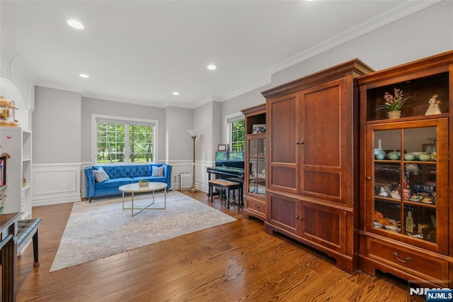 living room with dark wood finished floors, wainscoting, ornamental molding, recessed lighting, and a decorative wall