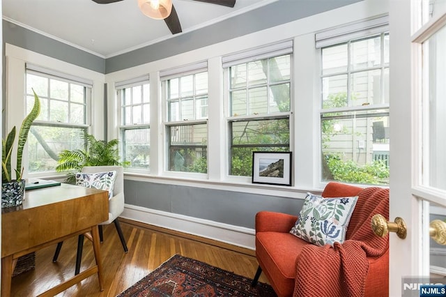 sunroom / solarium featuring crown molding, baseboards, a wealth of natural light, and wood finished floors