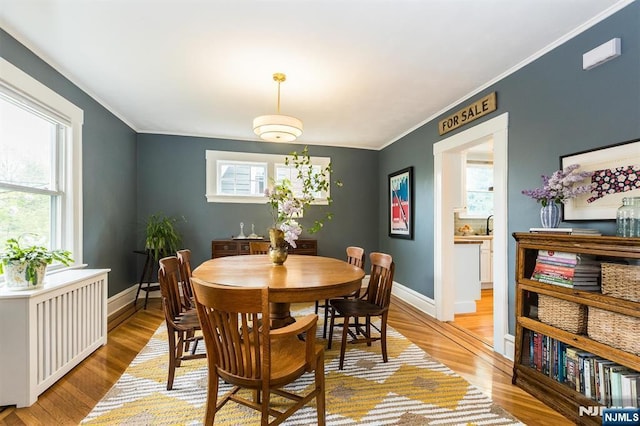 dining room featuring light wood-style floors, baseboards, and ornamental molding