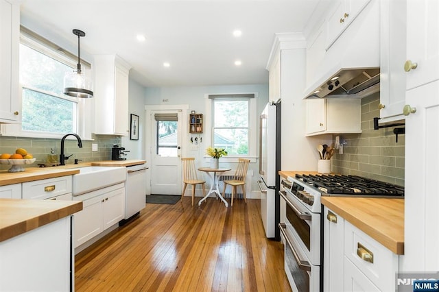 kitchen with a sink, white cabinets, under cabinet range hood, white appliances, and butcher block countertops