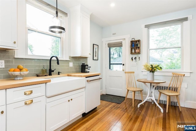 kitchen featuring light wood-type flooring, dishwasher, a sink, white cabinets, and butcher block counters