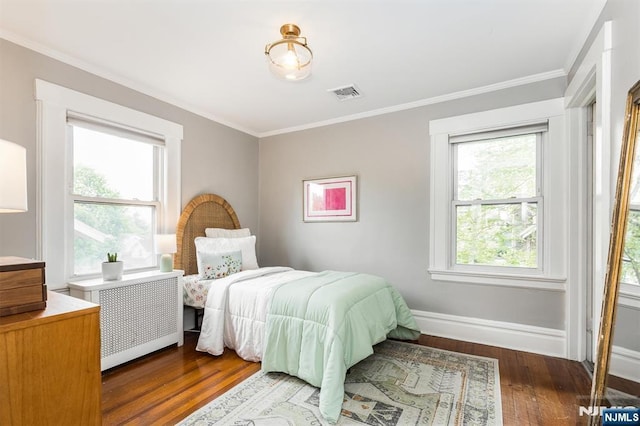bedroom featuring visible vents, crown molding, wood finished floors, baseboards, and radiator heating unit