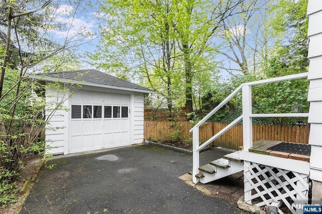 detached garage featuring fence and driveway