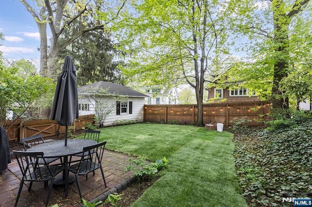 view of yard featuring a fenced backyard, outdoor dining space, and a patio area