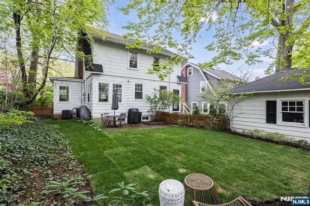 rear view of house with fence and a yard
