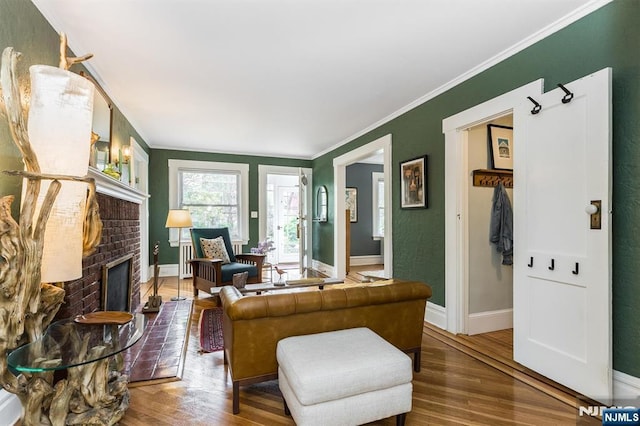 living area with baseboards, ornamental molding, wood finished floors, and a fireplace