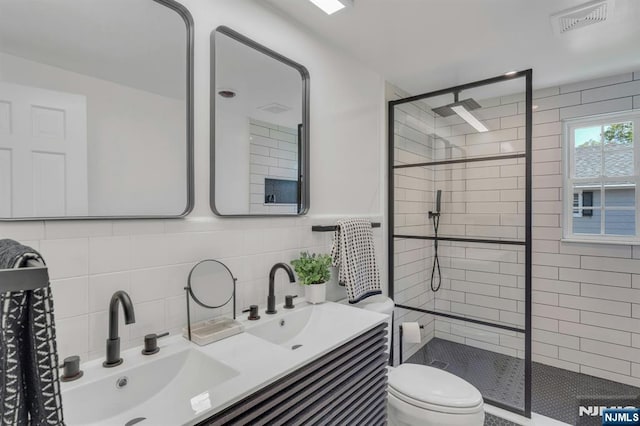 full bathroom featuring tile walls, visible vents, a stall shower, and a sink