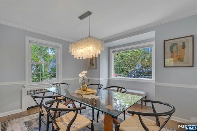 dining space featuring wood finished floors, radiator heating unit, ornamental molding, a chandelier, and baseboards