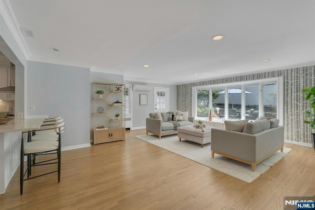 living room with radiator heating unit, ornamental molding, light wood-style flooring, an AC wall unit, and baseboards