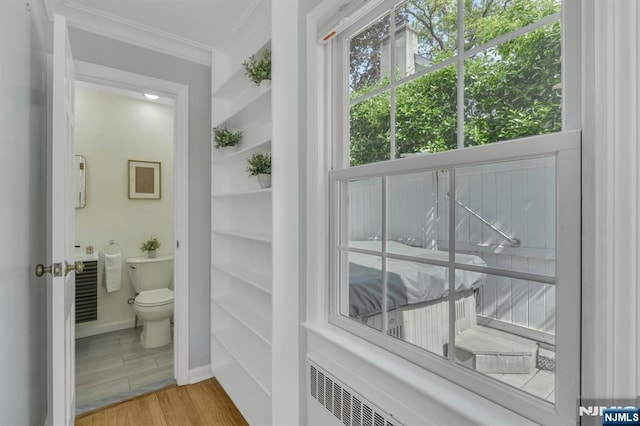 bathroom featuring toilet, ornamental molding, baseboards, and wood finished floors