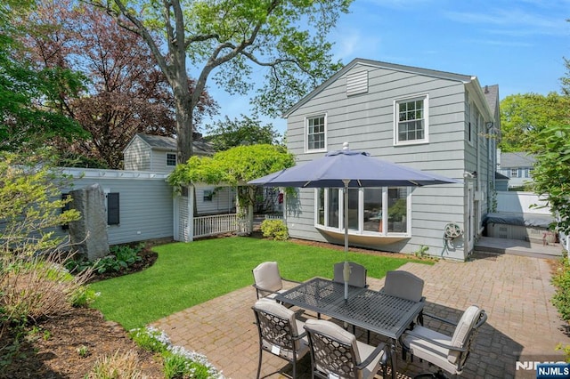 rear view of house with a yard, a patio, outdoor dining area, and fence
