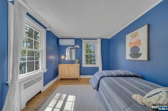 bedroom with ornamental molding, radiator, and a wall unit AC