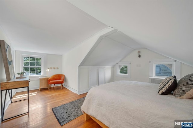 bedroom with baseboards, wood finished floors, and lofted ceiling
