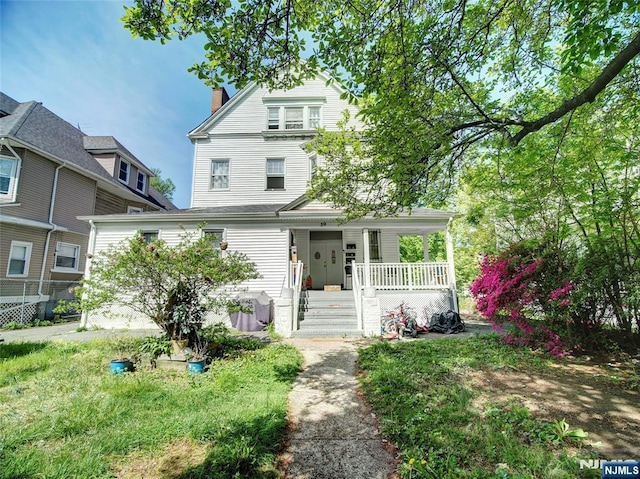 american foursquare style home featuring covered porch and a chimney
