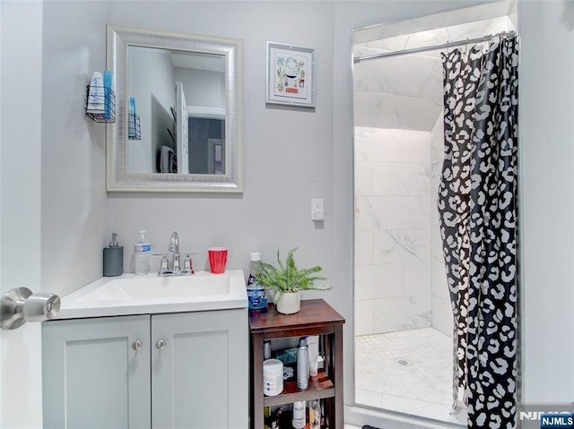 full bath with a tile shower and vanity