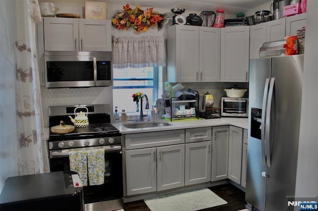 kitchen with backsplash, stainless steel appliances, a sink, and light countertops