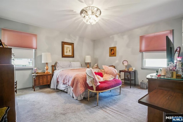 carpeted bedroom with baseboards, multiple windows, and a notable chandelier