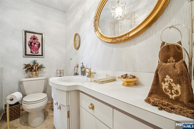 half bath with vanity, toilet, and wallpapered walls