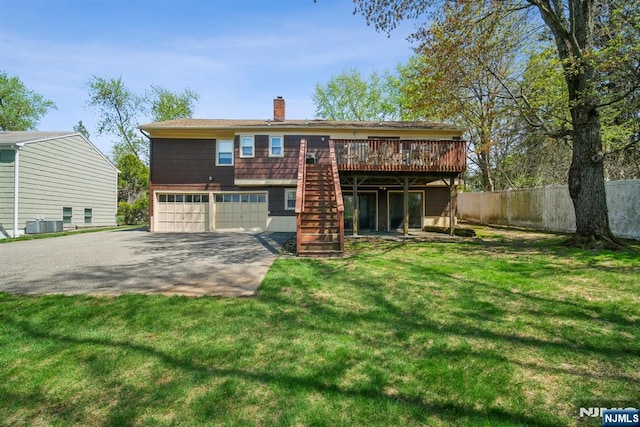 rear view of house with fence, a wooden deck, stairway, a chimney, and a yard