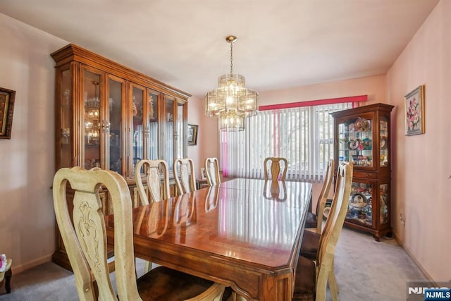 carpeted dining area featuring baseboards and a chandelier