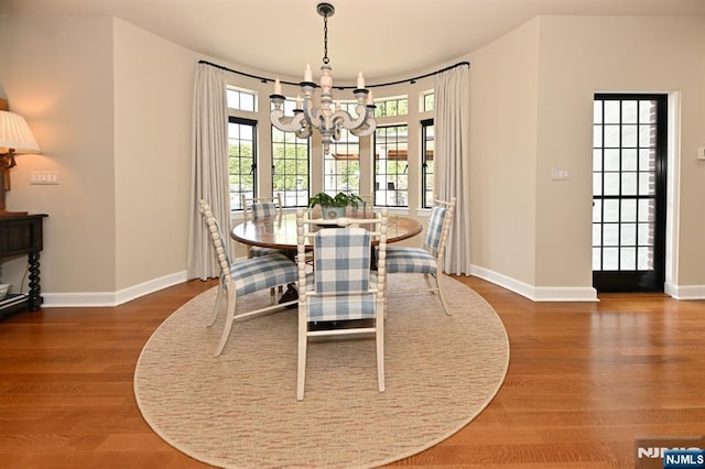 dining area featuring baseboards, a notable chandelier, a healthy amount of sunlight, and wood finished floors