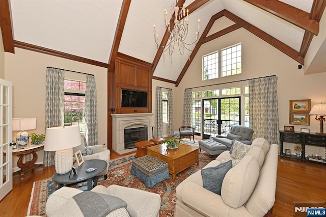 living area featuring beam ceiling, wood finished floors, high vaulted ceiling, and a large fireplace