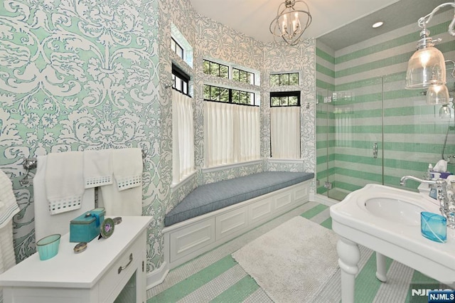 full bath featuring wallpapered walls, an inviting chandelier, a shower stall, and a sink
