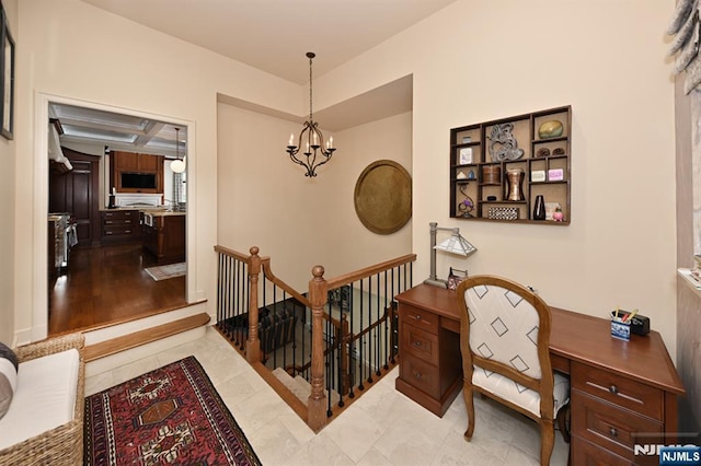 hallway with a notable chandelier, an upstairs landing, and coffered ceiling