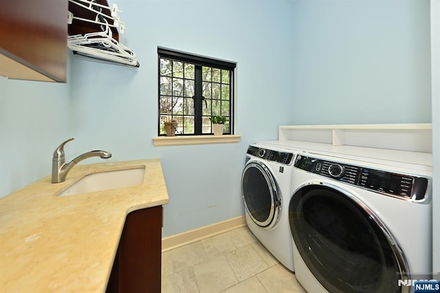 laundry area with washing machine and clothes dryer, baseboards, a sink, and cabinet space