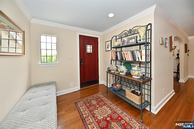foyer with arched walkways, ornamental molding, and wood finished floors
