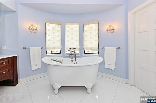 full bathroom with baseboards, a soaking tub, tile patterned floors, and vanity