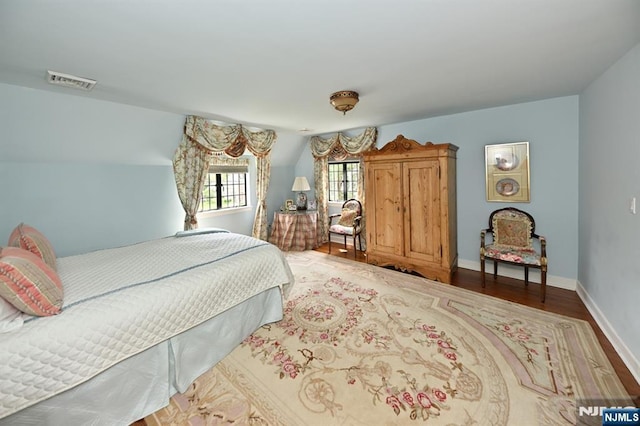 bedroom featuring baseboards, wood finished floors, and visible vents