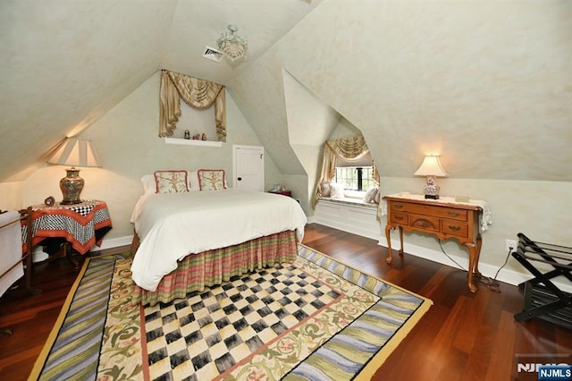 bedroom with vaulted ceiling, wood finished floors, and visible vents