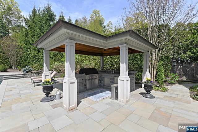 view of patio / terrace with grilling area, exterior kitchen, a gazebo, and fence
