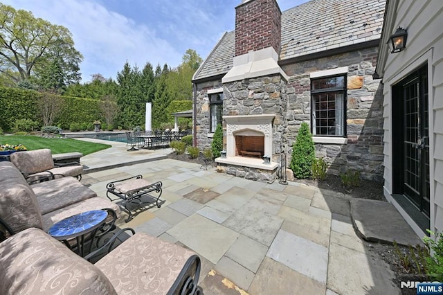 view of patio with an outdoor stone fireplace and a fenced in pool